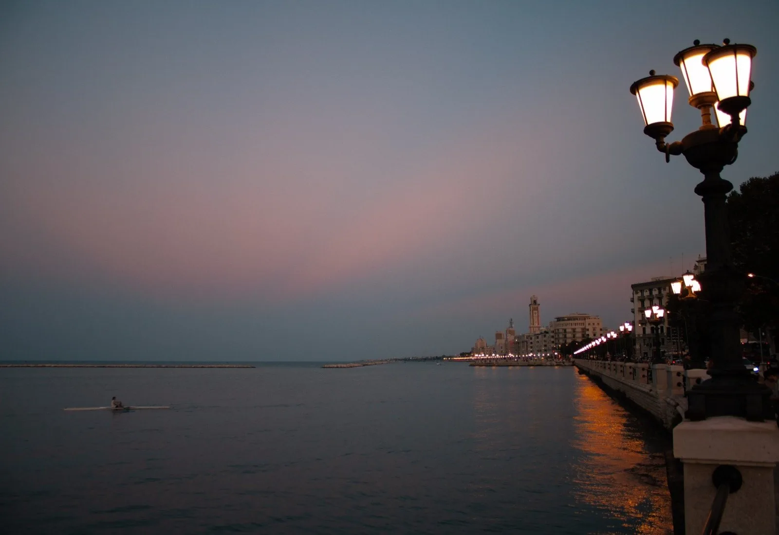 Il lungomare di Bari all'imbrunire, con i lampioni accesi e il mare calmo